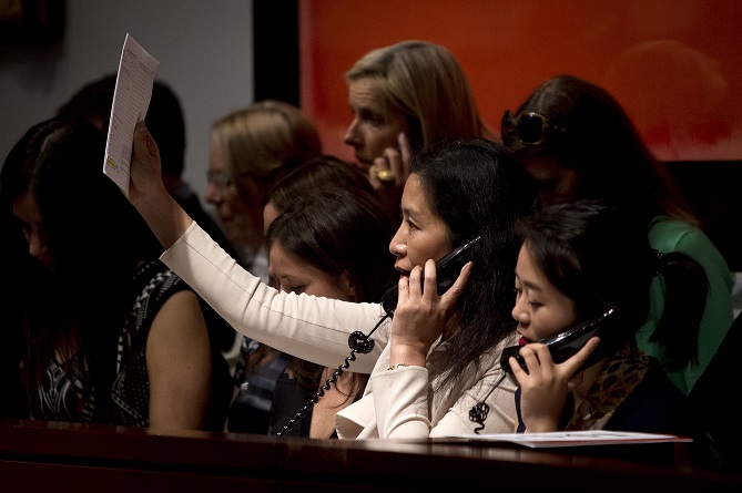 A Christie's employee working the phone holds up her bidders paddle during an auction at Christie's Auction House in the Manhattan borough New York
