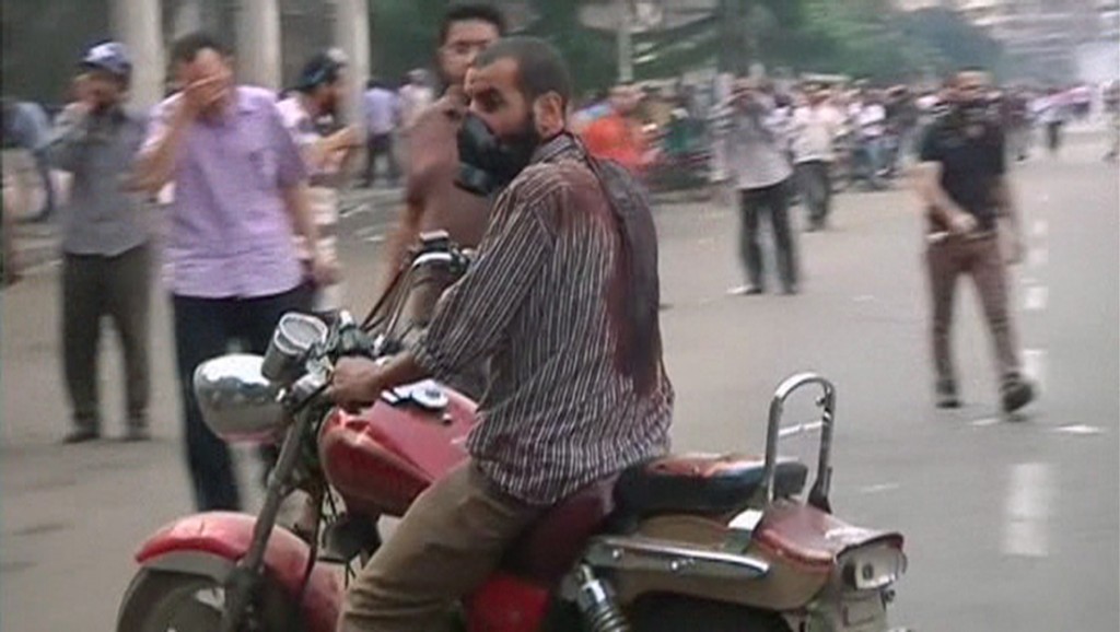 A man wearing a gas mask rides a motorcycle while wearing a blood-drenched shirt as security forces break up the protest camp at al-Nahda square in Cairo