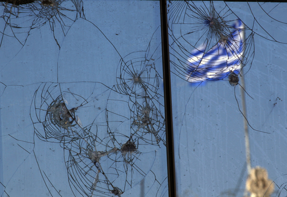 A Greek flag is reflected on a glass building damaged by recent civil unrest in central Athens