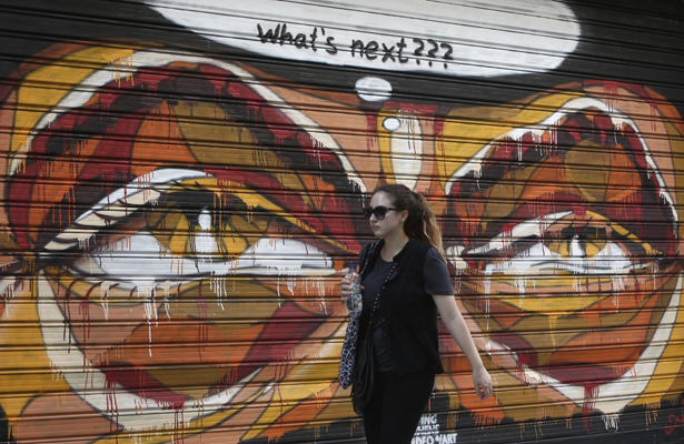 A woman walks in front of a graffiti painted on a shop shutter, in Athens