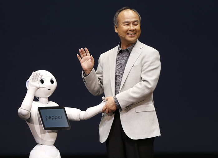 SoftBank Corp. Chief Executive Masayoshi Son waves with the company's human-like robots during a news conference in Urayasu