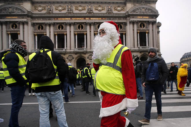epa07232362 A Yellow Vest protestor wearing a Santa Claus outfit attends a demonstration in front of the Opera in Paris, France, 15 December 2018. The so-called 'gilets jaunes' (yellow vests) is a protest movement, which reportedly has no political affiliation, that continues protests across the nation over high fuel prices. EPA/IAN LANGSDON
