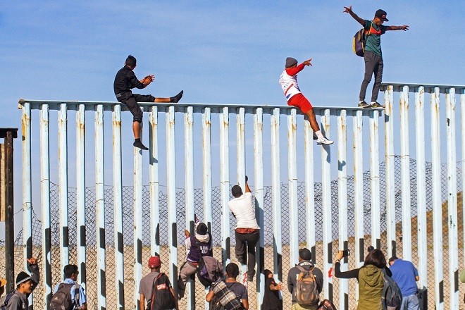 epaselect epa07163836 Members of the caravan of Central American migrants climb the border wall in Tijuana, Baja California, Mexico, 13 November 2018. Dozens of Central American migrants reached the US-Mexico border, and some climbed the fence that divides both countries, a first step in their final goal of entering the United States. EPA/JOEBETH TERRIQUEZ