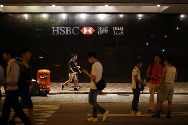 Protesters walk by a closed HSBC bank branch near the government headquarters in Hong Kong