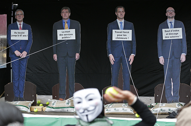 Protesters throw balls at portraits of members of the Belgian government during a march through central Brussels