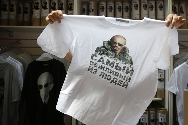 A shop assistant sells T-shirts which are printed with images of Russia's President Vladimir Putin, at GUM department store in central Moscow