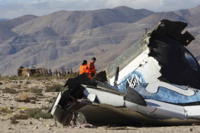 Sheriffs' deputies look at wreckage from the crash of Virgin Galactic's SpaceShipTwo near a broken down house near Cantil, California