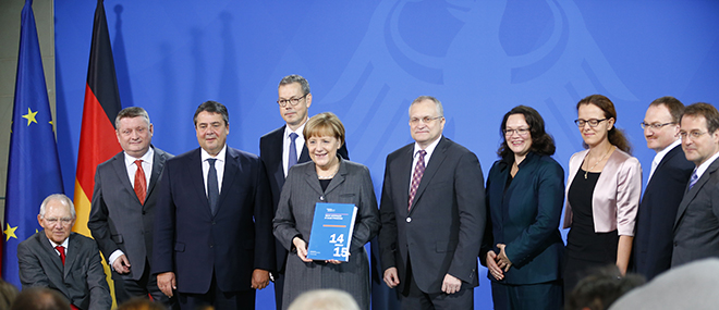 German Chancellor Merkel poses with members of SVR after they presented their 2014/2015 report in Berlin