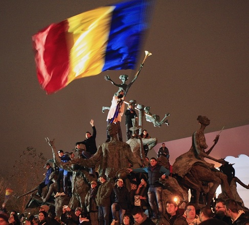 Supporters of Romanian presidential candidate Klaus Iohannis celebrate his victory in the election run-off, from atop a statue in central Bucharest