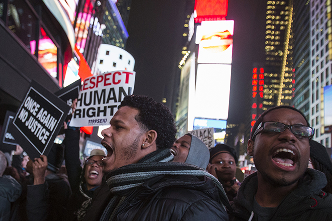 Protesters, demanding justice for the death of Eric Garner, hold placards while shouting slogans through Times Square, in the Manhattan borough of New York