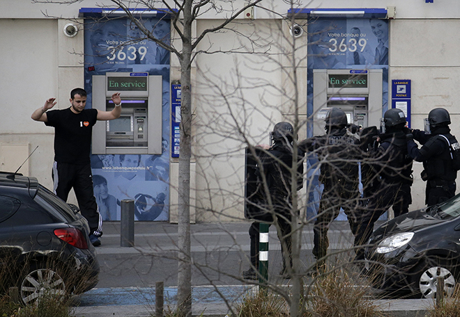 A suspect in a hostage taking situation is detained by members of special French RAID forces outside the post offices in Colombes outside Paris