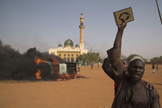 A man holds a copy of the Koran during a protest against Niger President Issoufou's attendance last week at a Paris rally in support of French satirical weekly Charlie Hebdo, in Niamey
