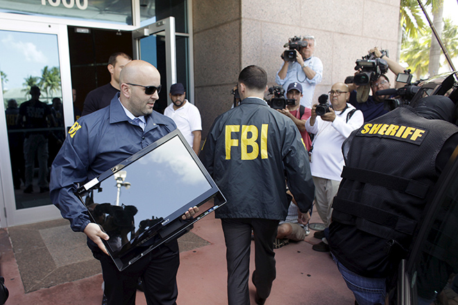 An FBI agent brings out a computer after an operation inside the CONCACAF (Confederation of North, Central America and Caribbean Association Football) offices in Miami Beach, Florida May 27, 2015. The world's most popular sport was plunged into turmoil on Wednesday as seven powerful soccer figures were arrested on U.S. corruption charges and faced extradition from Switzerland, whose authorities also announced a criminal investigation into the awarding of the next two World Cups. REUTERS/Javier Galeano  - RTX1ETW3