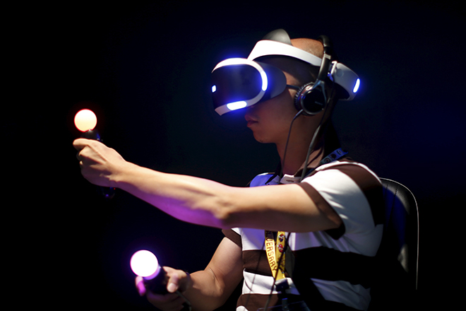 A man plays Sony's Project Morpheus "London Heist" video game with a virtual reality headset and move controllers at the Sony PlayStation booth at the Electronic Entertainment Expo, or E3, in Los Angeles, California, United States, June 16, 2015. REUTERS/Lucy Nicholson  - RTX1GTA2