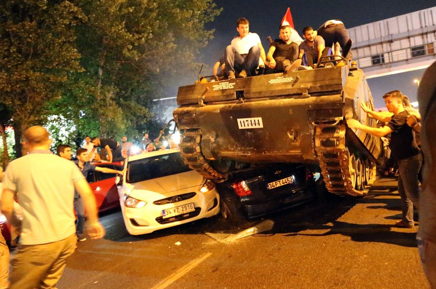 epaselect epa05427134 People on a tank run over cars on a road in Istanbul, Turkey, 16 July 2016. Turkish Prime Minister Yildirim reportedly said that the Turkish military was involved in an attempted coup d'etat. The Turkish military meanwhile stated it had taken over control.  EPA/TOLGA BOZOGLU